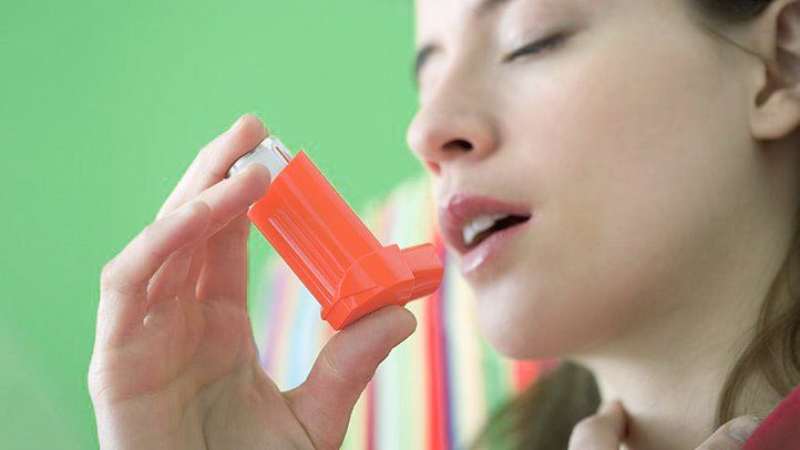 a woman with asthma using an inhaler